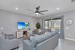 A modern living room with grey sofas, a flat-screen TV, and a ceiling fan. - Star Wars Game Room • Minions & Themed Rooms • Private Pool • Near Disney (Davenport)
