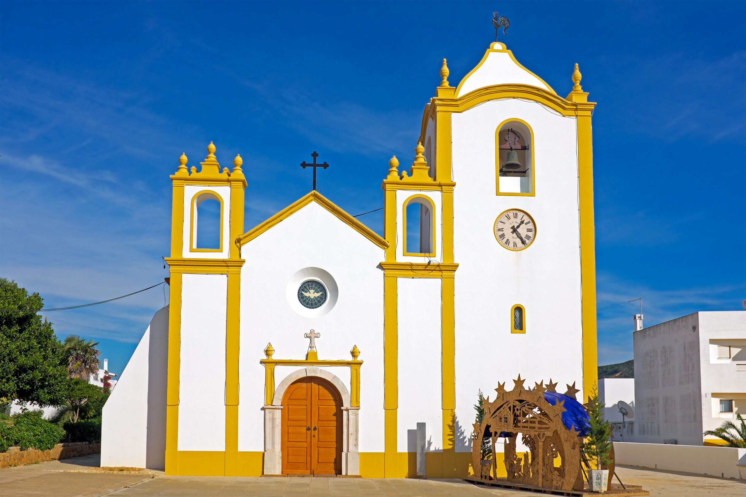 A church with a bell tower, a clock, and a nativity scene.