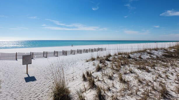 A beach with a wooden fence and a sign indicating beach warning flags. - Market Street Inn 434 - Studio with 2 queen beds, close to Baytowne Wharf! (Miramar Beach)