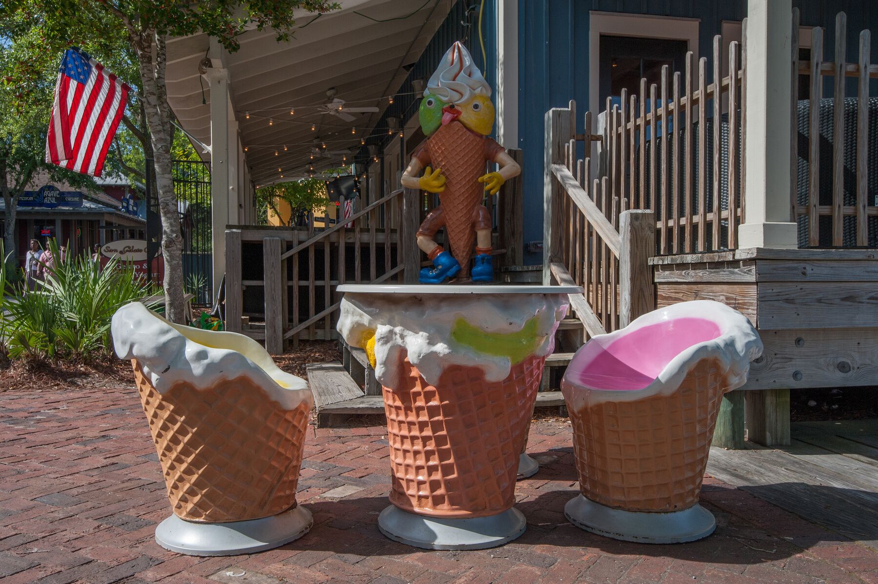 Une sculpture décorative en forme de glace représentant un personnage portant un chapeau conique, placée sur une table avec trois pots de glace.