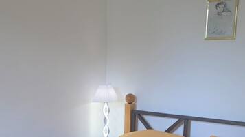 Una cama con cabecera de madera, una lámpara de noche y dos cuadros en la pared.