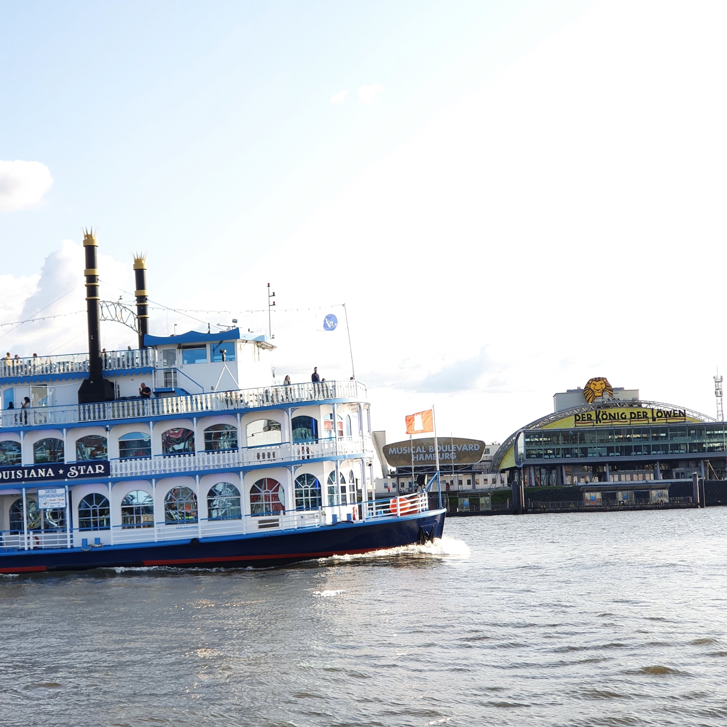 Un barco de crucero fluvial llamado 'Louisiana Star' con varias cubiertas y una bandera.