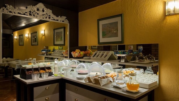 Un buffet proposant une variété de plats et de boissons, notamment des fruits et des produits laitiers, installé dans un espace de restauration bien éclairé, agrémenté d’éléments décoratifs sur les murs et de tableaux encadrés.