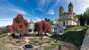 Un jardin à la française, avec des allées disposées de manière symétrique et un grand bâtiment flanqué de deux tours.