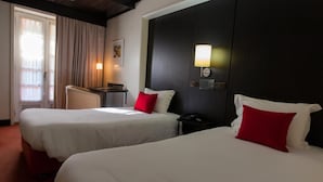 Une chambre d’hôtel avec deux lits, un bureau, une chaise et une lampe.