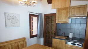 Una mesa de comedor de madera con sillas, una cocina con armarios de madera y un lavavajillas, y un mapa en la pared.
