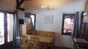 Un comedor acogedor con una mesa y bancos de madera, una araña y un mapa en la pared.