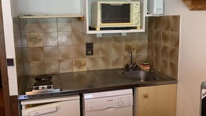 A compact kitchen with wooden cabinets, a microwave, a sink, and a dishwasher. - 100m from resort center, 1st floor, view village, balcony, tv, 21m², Champagny-en-Vanoise (Champagny-en-Vanoise)