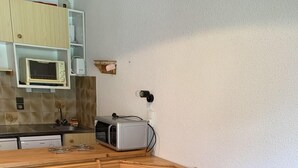 A wooden dining table with six chairs, a microwave, and a toaster oven in a kitchen. - 100m from resort center, 1st floor, view village, balcony, tv, 21m², Champagny-en-Vanoise (Champagny-en-Vanoise)