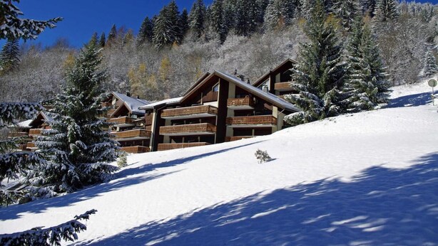 A wooden lodge with multiple balconies, surrounded by snow-covered trees and a clear blue sky. - 100m from resort center, 1st floor, view village, balcony, tv, 21m², Champagny-en-Vanoise (Champagny-en-Vanoise)