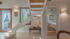 Ein modernes Interieur mit einer Wendeltreppe, einer Holzbank und Blick in ein Schlafzimmer.
