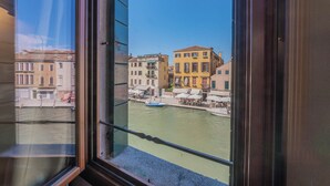 Blick aus einem Fenster auf einen Kanal mit Gebäuden und einem Boot.