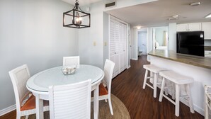 A dining area with a round table, white chairs, and a woven rug.
