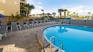 A pool area with lounge chairs and a brick walkway.