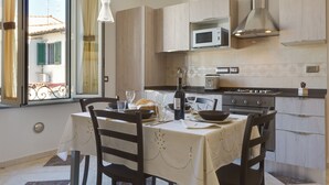 A modern kitchen with a dining table set for two, a microwave, stove, and a large window with curtains. - 💥💥💥"Marte Suite" -  in the heart of Florence! A/C - WiFi superfast! 💥💥💥 (Firenze)