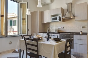 Une cuisine moderne avec une table à manger pour deux personnes, un four à micro-ondes, une cuisinière et une grande fenêtre avec des rideaux.