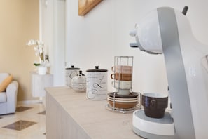 Un comptoir de cuisine avec une machine à café, une pile de tasses à café et un service à thé.
