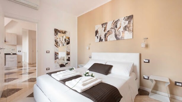 A modern hotel room with a large bed, a bedside table, a wall-mounted light, and artwork. - 💥💥 💥"Marte Suite" -  in the heart of Florence! A/C - WiFi superfast! 💥💥💥 (Firenze)