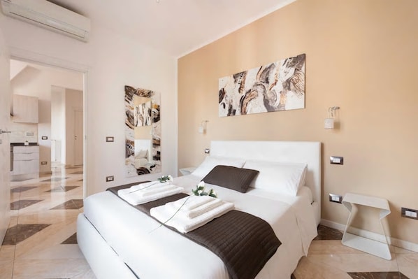 Une chambre d’hôtel moderne avec un grand lit, une table de chevet, une lampe fixée au mur et des œuvres d’art.