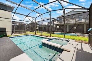 A swimming pool with a hot tub, surrounded by a covered area with a metal frame structure.