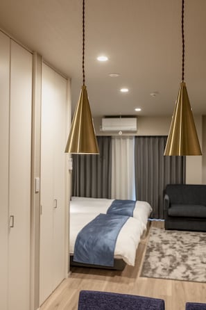 A modern hotel room with a bed, a sofa, and a hanging gold pendant light. - hotel aima (Tokyo)