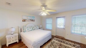 A bedroom with a bed, nightstands, a ceiling fan, and a window with blinds.