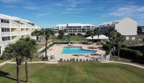 Un hôtel doté d’une piscine entourée de palmiers et d’un terrain de jeux.