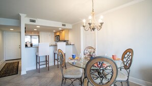 A dining area with a glass table, metal chairs, and a chandelier. - The Beach is Calling You to 324 (Biloxi)