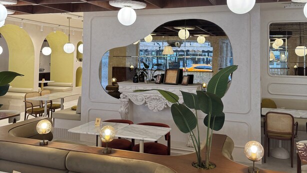 Interior de restaurante con techos altos, vigas a la vista y una variedad de opciones de asientos, incluyendo cabinas y mesas.