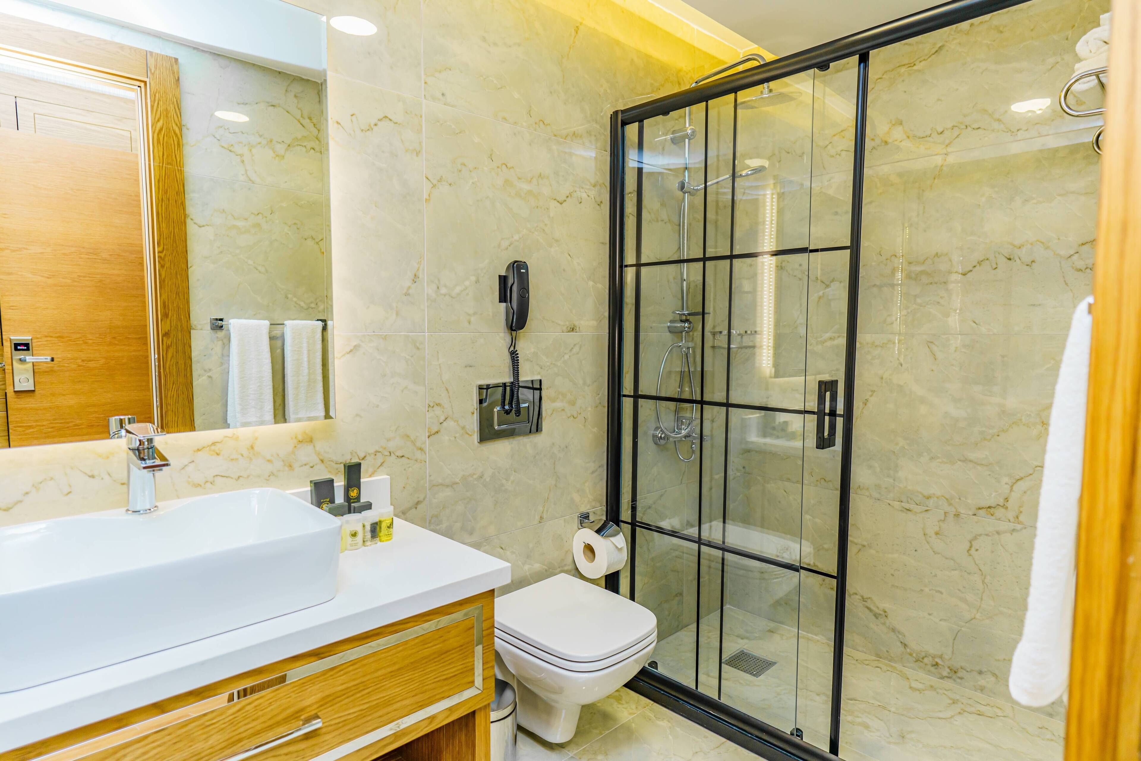 Un baño moderno con un lavamanos grande, inodoro y ducha con cerramiento de vidrio.