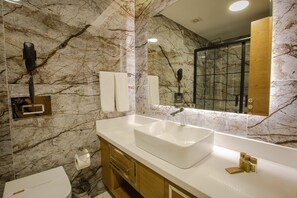 A bathroom with a marble wall, a large sink, and a mirror. - Bahçelievler Hotels (Ankara)
