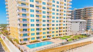 Un hôtel à plusieurs étages doté de balcons, d’une piscine et d’un espace de plage.