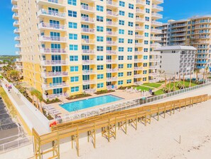 Ein mehrstöckiges Hotel mit Balkonen, einem Pool und einer Strandanlage.