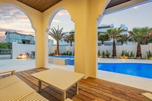A covered outdoor area with a pool, wooden flooring, and a table. - Seaclusion at Seagrove|Private Deeded Beach|Resort Style Heated Pool (Santa Rosa Beach)