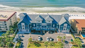 A beachfront hotel with a parking lot, multiple floors, and a beach view.