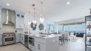 A modern kitchen with stainless steel appliances, a large island, and a view to the ocean.