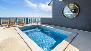 A swimming pool with lounge chairs and a view of the ocean.