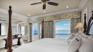 Une chambre spacieuse avec un grand lit, un ventilateur de plafond et une vue sur l’océan.
