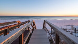 Une promenade en bois menant à une plage, avec un ciel dégagé.