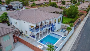 A two-story house with a swimming pool, a covered patio, and a fenced yard.