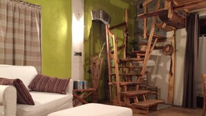 Un salon avec un canapé blanc, une échelle en bois et une petite table sur laquelle se trouve un haut-parleur.