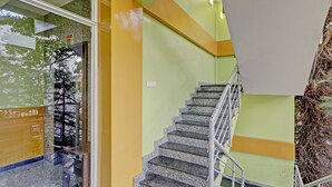 Una escalera con escalones de granito y barandilla de metal, que lleva a un rellano con un interruptor de luz.