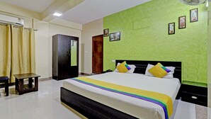 Una habitación de hotel con cama, una mesita, un armario y una puerta.