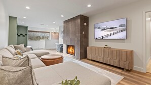 A modern living room with a fireplace, a large TV, and a view of a snowy landscape. - 3 Bedrooms, 3 Baths, Gas Fireplace | Sleeps 8 | Moose Mgt 536 (Park City)