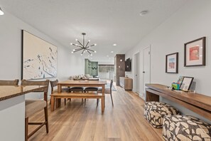 Un interno moderno con un tavolo da pranzo in legno, panche, un divano e una TV appesa al muro.