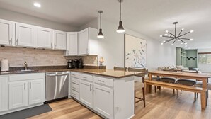 A modern kitchen with white cabinets, a wooden countertop, and a dining area with a wooden table and chairs. - 3 Bedrooms, 3 Baths, Gas Fireplace | Sleeps 8 | Moose Mgt 536 (Park City)