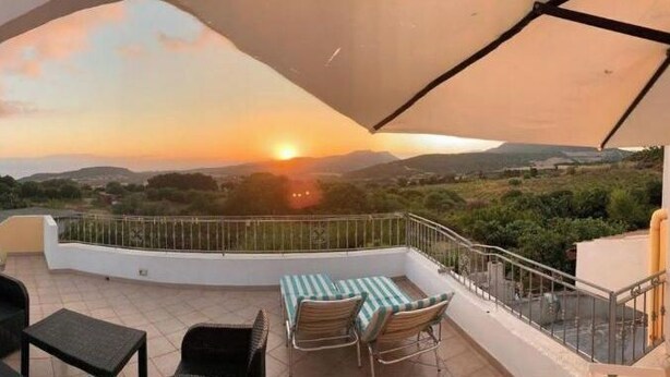 A terrace with a view of the sunset, outdoor furniture, and a covered area. - Mare Natura (Castelsardo)