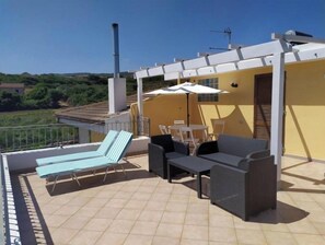 A terrace with a pool, lounge chairs, a table, and an umbrella. - Mare Natura (Castelsardo)