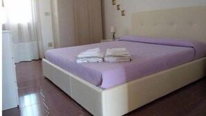 A hotel room with a bed, a nightstand, a lamp, and a window with curtains. - Mare Natura (Castelsardo)