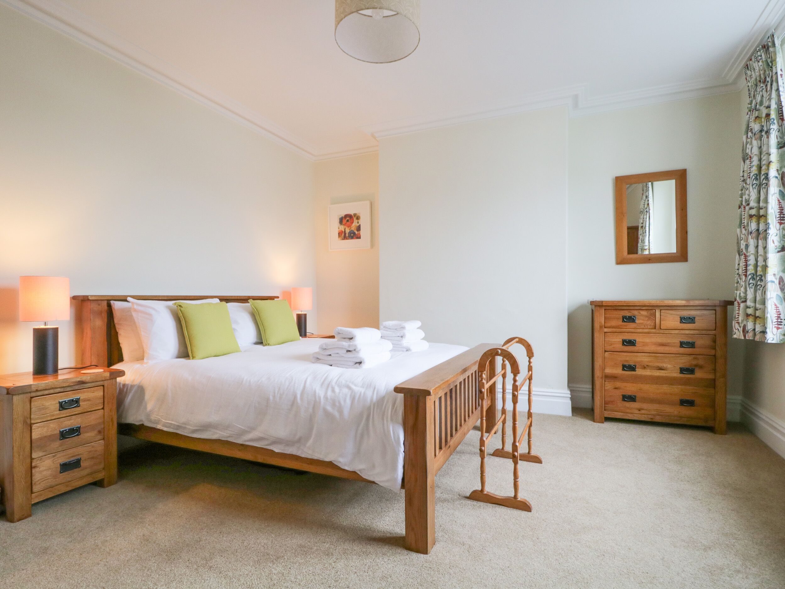 A neatly arranged bedroom with a wooden bed, bedside tables, a wooden chair, and a dresser.